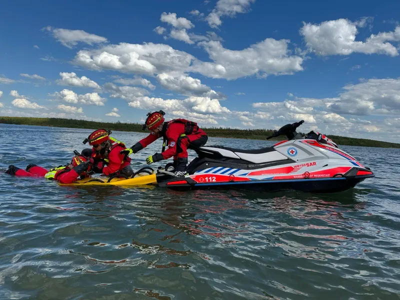 Zwei Wasserretter ziehen eine Person auf das Rescue Board am Rescue Watercraft